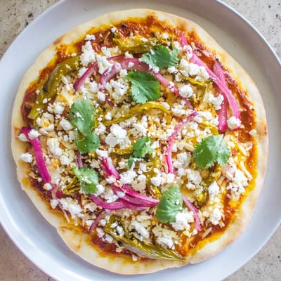 Vibrant vegetarian pizza featuring charred poblano strips, red onion, and creamy queso fresco